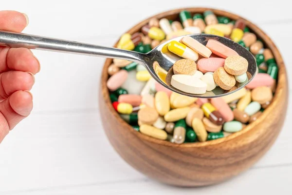 Colorful capsules and tablets in a spoon, close-up