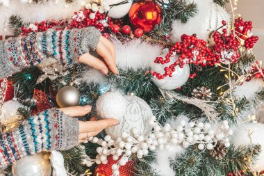 Noel ağacı süslemesi, kadın elleri bir dala top asıyor.