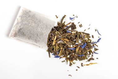 Üst manzara, dağınık yeşil çay ve mavi yapraklı çay poşeti.