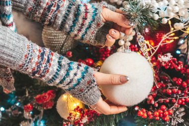 Yakından, beyaz toplu kadın elleri Noel 'i süslüyor. 