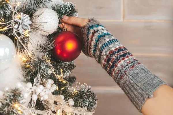 Yakın plan, el Noel ağacına kırmızı bir top asar.