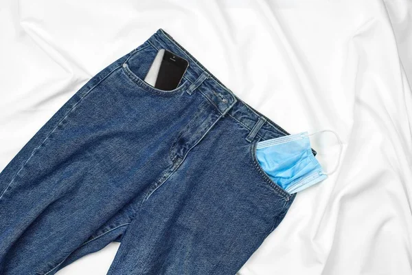 Jeans with a face mask and smartphone in the pocket