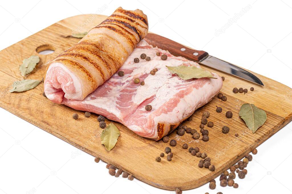 Pork bacon on a wooden kitchen board with spices and a knife
