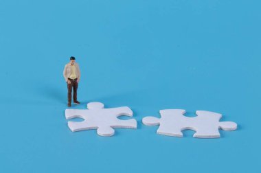 Minyatür adam iki yapboz parçasına bakıyor.