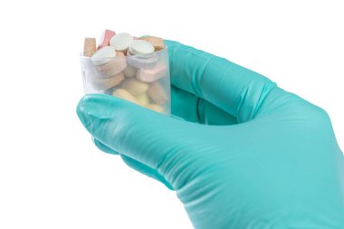 Doctor's hand holding a plastic glass with pills