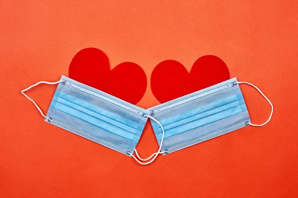 Two heart-shaped paper cuts under protective face masks