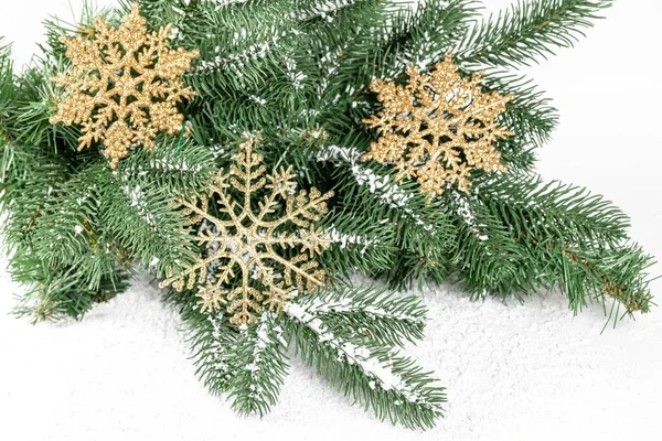 Noel ağacı dalları, altın kar taneleri ve kar.