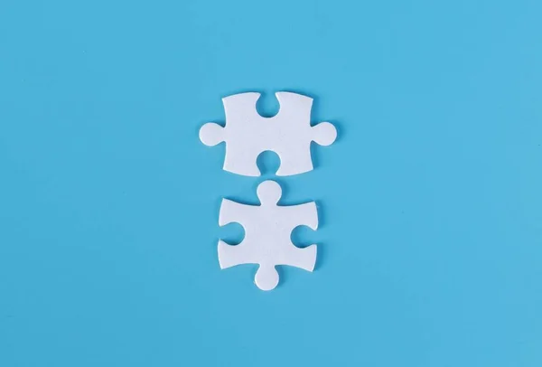 Two pieces of jigsaw puzzle on blue background