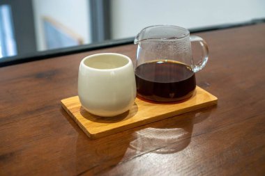 Tahta servis yapan Boa 'nın üzerinde sıcak damlayan kahve ile küçük cam sürahi.