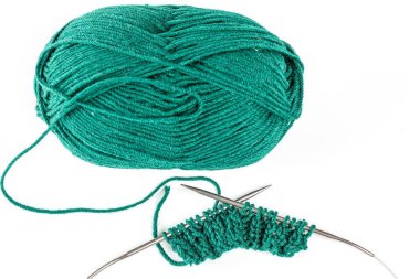 Top view, ball of green yarn with knitting needles