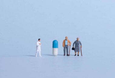 Yaşlı bir çift ve açık mavi arka planda hapları olan bir doktor.