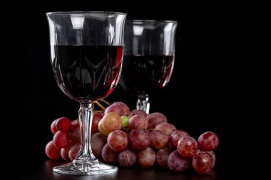 Sırtında bir dal taze üzümle iki kadeh şarap.