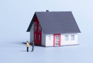 İki işadamı bir evin önünde el sıkışıyor.