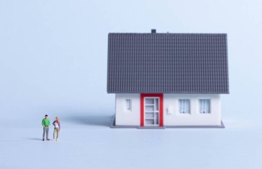 Açık mavi arka planda evi olan çift.