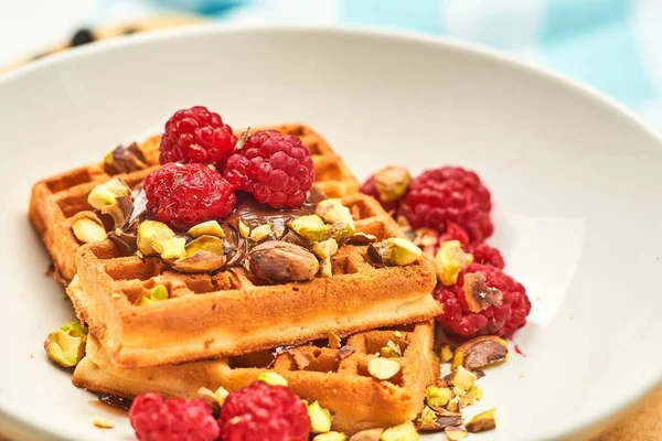 Healthy breakfast with sweet waffles covered with pista and rasp