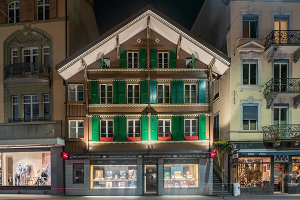 Small Swiss Old House Wooden Window Shutters Interlaken Night lizenzfreie Stockfotos