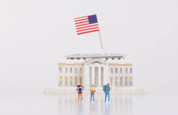 Miniature travelers stading in front of the White House with USA