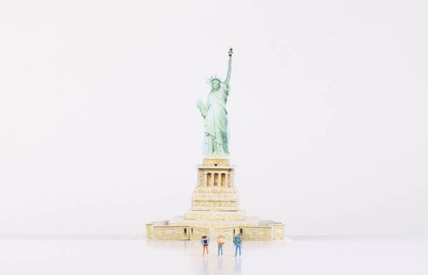 Миниатюрные путешественники, стоящие перед статуей Свободы