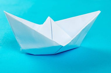 Mavi arka planda beyaz kağıt gemi