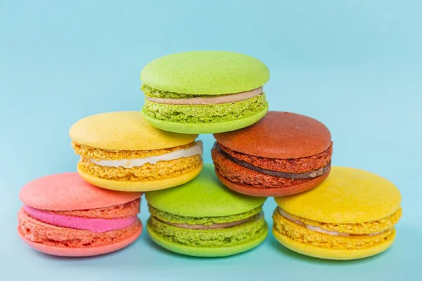 Yellow, pink, green and brown macaroon cookies on a blue backgro