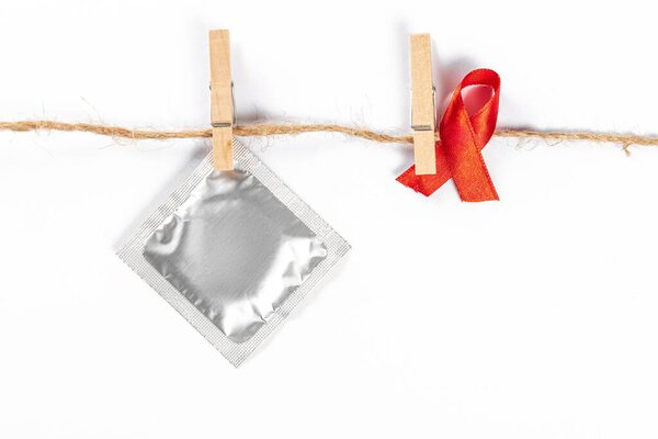 Red ribbon and condom with clothespins hanging on a rope