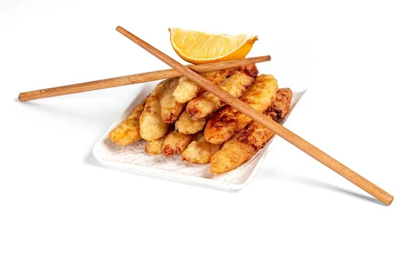 Fried fish sticks with a slice of lemon and chopsticks