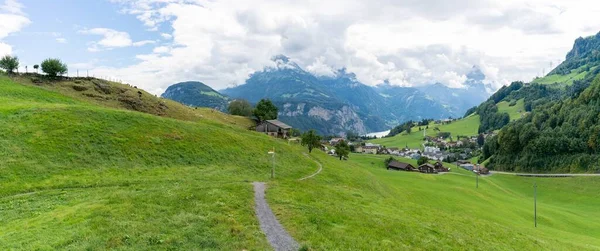 Panorama of Swiss green hills with path, village, mountains and lake Lucerne