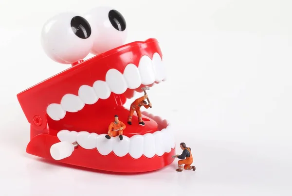 Minyatür insanlar beyaz sırt grubunda diş temizliyor.