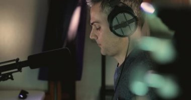 Müzik yapımcısı, bir projenin ses katmanlarını kendi stüdyosundaki kayıt sırasında yerleştirmek için şarkı söylüyor.