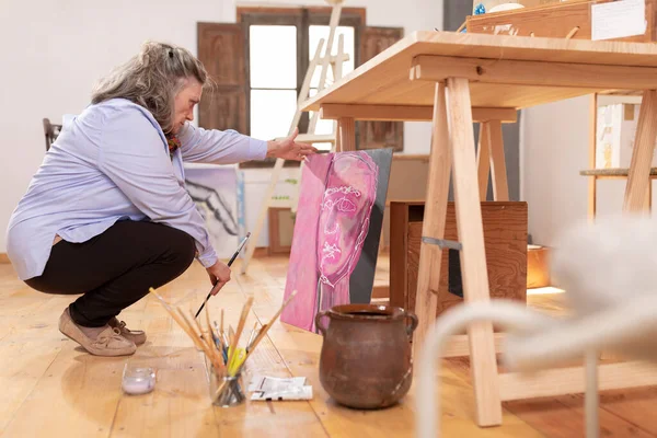 Mature Artist Woman Squatting Her Workshop Contemplating One Her Works — Stock Photo, Image