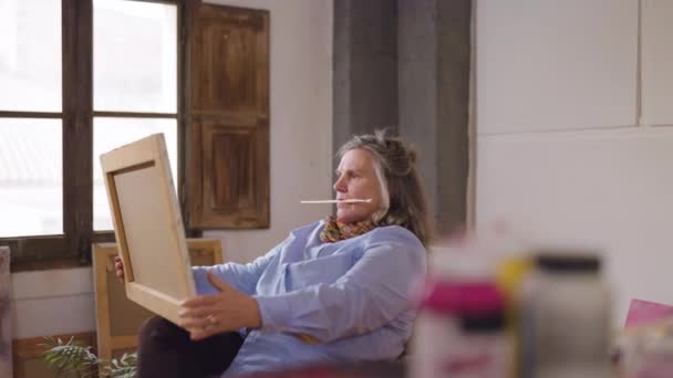 成熟的女艺术家在她的工作室里看到了她在他闲暇时间创作的一部作品 — 图库视频影像