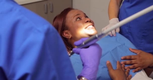 歯の衛生士が歯のクリニックで歯肉炎を防ぐため歯茎や歯をチェックしてきれいにする前に黒人女性患者の話と笑顔 — ストック動画