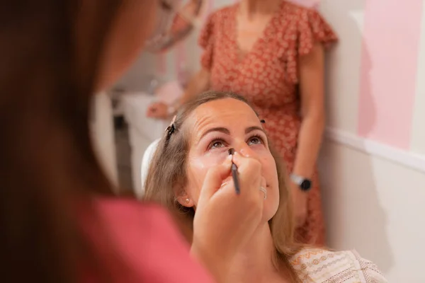 Kvinde Kunde Sidder Stolen Mens Kosmetologen Bruger Eyeliner Makeup Session - Stock-foto