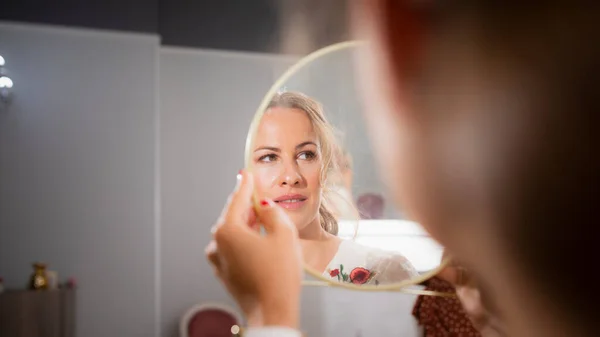 美容室のお客様の美しい女性は メイクアップセッションの後 手鏡で自分自身を見て — ストック写真