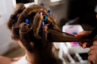 Kuaför salonundaki kuaförde kıvrılan bir kadın müşterinin saçını kapat.