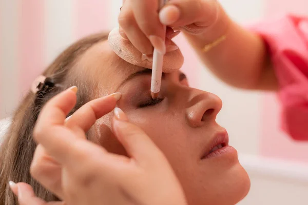 A beautician woman drawing eye shadow on her customers eyelid during a makeup session at the beauty salon