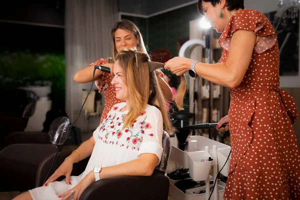 Two Female Hairdressers Work Her Clients Hairstyle While She Remains — ストック写真