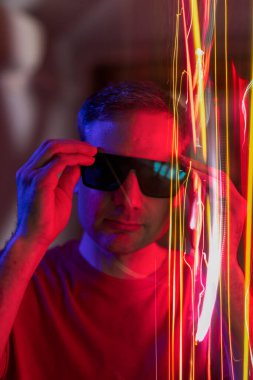 Young adult looks at the camera while repositioning his sunglasses that somehow hide part of his identity in the metaverse