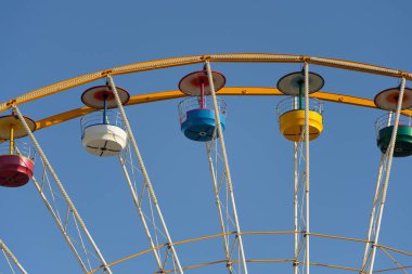 Fuar alanındaki dönme dolabın renkli eksozlarına yakın plan, arka planda mavi gökyüzü