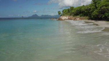 Quadracopter videosu, Karayipler adasındaki mavi gökyüzü ve turkuaz deniz suyunun tepesine kadar alçak irtifada çekildi. Tatil için Pointe de Marin. Simetrik sinematik video.
