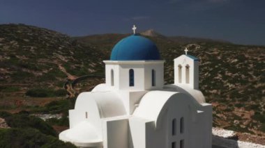 Yunanistan 'da mavi kubbeli güzel bir kilisenin insansız hava aracı çekimi. Mavi okyanus ve dağlardan oluşan güzel bir manzarayla Amorgos Adası' ndaki kayalık bir tepede. Arka plandaki okyanus gibi çatı rengi
