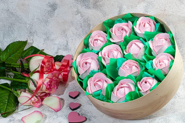 Handgemaakte marshmallows in houten verpakkingen op een lichte achtergrond met bloemen. Het concept van de feestdagen Vrouwendag en Valentijnsdag. — Stockfoto