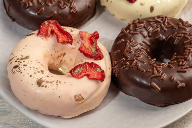 Hafif arka planda beyaz ve siyah çikolatalı el yapımı çörekler. Yakınlarda çiçekler var. Kadınlar Günü, Sevgililer Günü. Boşluğu kopyala.