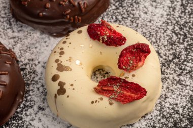 Hafif arka planda beyaz ve siyah çikolatalı el yapımı çörekler. Yakınlarda çiçekler var. Kadınlar Günü, Sevgililer Günü. Boşluğu kopyala.