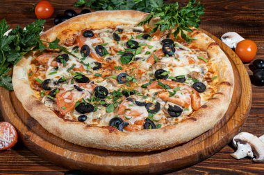 Pastırmalı, peynirli, otlu ve kirazlı pizza. Ahşap zemin üzerinde mozzarella, karides ve ahtapot, midye ve diğer ürünlerle.
