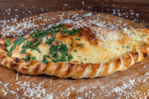 Calzone pizza con pancetta e formaggio, erbe aromatiche e pomodorini. Con mozzarella, gamberetti e polpi, cozze e altri prodotti su fondo di legno. — Foto Stock