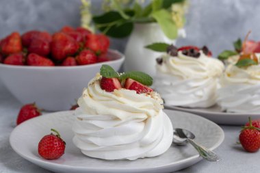 Krem şantili ve taze çilekli Pavlova kremalı kekler, nane yaprağı. Seçici odaklanma. Boşluğu kopyala.