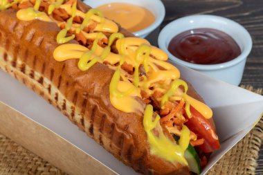 Domatesli, mısırlı, biberli, salatalıklı ve marullu sosisli sandviç. Kırmızı arka planda. Fast food. Boşluğu kopyala