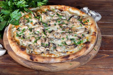 Pizza with bacon and cheese, herbs and cherry tomatoes. With mozzarella, shrimp and octopus, mussels and other products on a wooden background. fast food