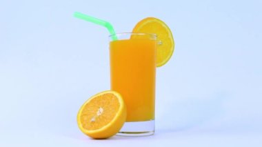 Bir bardak portakal suyu, portakal dilimli meyve, beyaz arka planda yeşil pipo ile izole edilmiş.